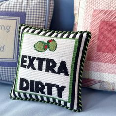 two decorative pillows with the words extra dirty on one and another pillow that says,