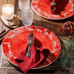 two plates with red napkins and silverware are on a table set for christmas dinner