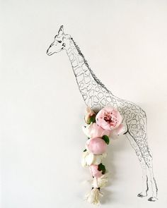 a giraffe standing next to a bunch of flowers on top of a white wall