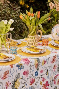 a table topped with plates covered in flowers and vases filled with tulips