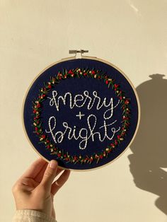 someone is holding up a hand embroidered christmas ornament with the words merry and bright on it