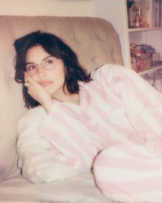 a woman wearing glasses laying on top of a bed