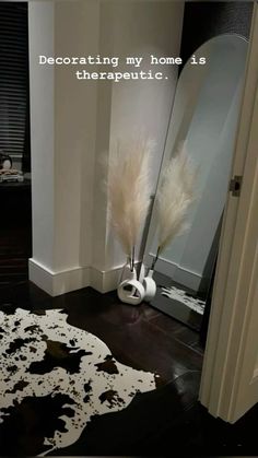 a white vase sitting on top of a black and white floor next to a mirror