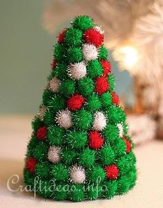 a small green christmas tree with red and white balls on it's top, sitting on a table