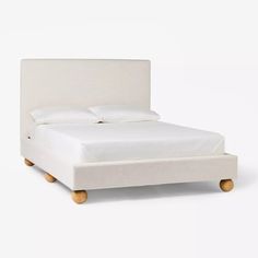 a bed with white linen and wooden legs