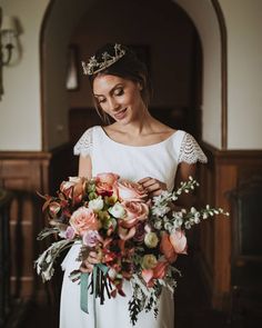 a woman in a white dress holding a bouquet of flowers and wearing a tiara