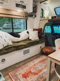 the interior of a camper with a couch, table and rugs on the floor