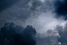 a person riding a horse in the middle of a field with dark clouds behind them