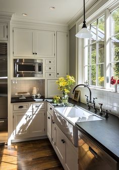 a kitchen with white cabinets and stainless steel appliances, along with flowers on the counter