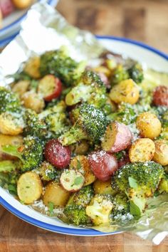 a plate full of broccoli and potatoes covered in powdered sugar on a wooden table