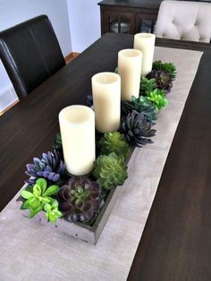 some candles are sitting on a table with succulents