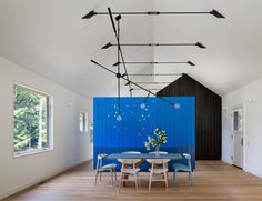 a dining room with blue walls and wooden flooring is seen in this modern house