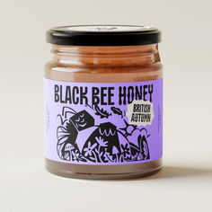 a jar of black bee honey sitting on top of a table