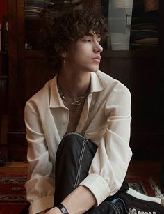 a young man sitting on the floor in front of a rug