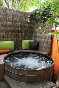 a hot tub sitting on top of a wooden deck next to a lush green wall