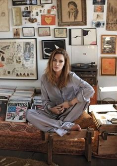 a woman sitting on top of a couch in front of a wall covered with pictures