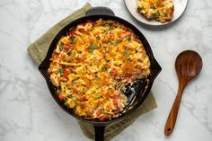 a casserole dish on a table next to a wooden spoon