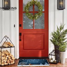 a red front door with a wreath and firewood on the step next to it