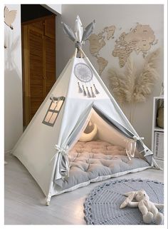 a white teepee tent sitting on top of a floor next to a stuffed animal