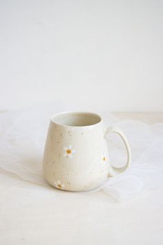 a white coffee cup with gold speckles on the inside sits on a table