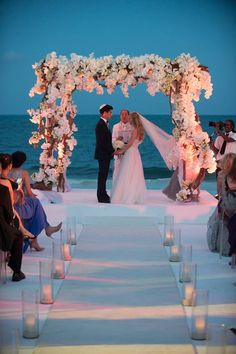 a bride and groom are standing under an arch decorated with flowers at the end of their wedding ceremony