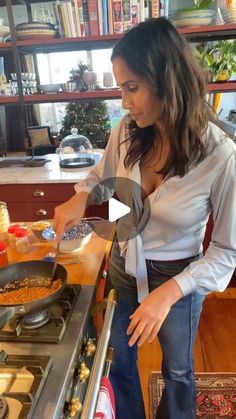 a woman standing in front of a stove cooking food on top of a frying pan