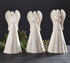 three white angel figurines sitting on top of a table