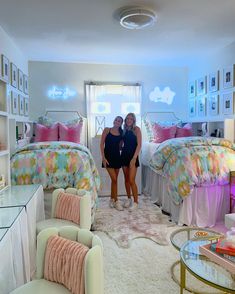 two women standing in a bedroom next to each other with pink and blue decor on the walls