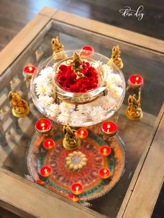 a glass table topped with lots of flowers and candles next to a tray filled with food