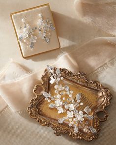 two brooches are sitting on a piece of cloth next to an ornate frame