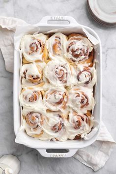 a white casserole dish filled with cinnamon rolls