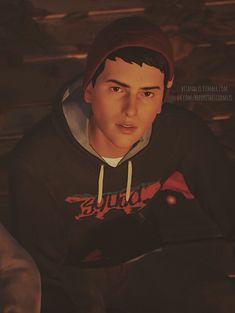 a young man wearing a black hoodie and a red beanie is sitting down