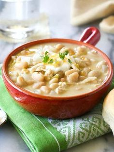 a red bowl filled with white bean soup on top of a green and white towel