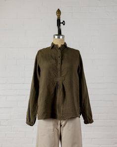 Long sleeve top with a small collar to wear up or down, mother of pearl button front and cuffs. Small gather at bottom of button front. Easy to wear on it's own, or layered under another top, jacket or sweater.  100% Linen. Made in the U.S.A. All of our pieces have been pre washed and dried to minimize any shrinkage. W Long Sleeve Linen Tops For Layering, Blouse With Buttons And Fold Down Collar, Cotton Tops With Cuffed Sleeves For Fall, Fall Cotton Tops With Cuffed Sleeves, Collared Linen Blouse For Fall, Fall Collared Blouse With Placket, Relaxed Fit Blouse With Cuffed Sleeves For Fall, Relaxed Fit Blouse With Button Cuffs For Casual Gatherings, Daywear Blouse With Fold Down Collar And Buttons