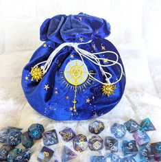 This cleric multi pocket dice bag is made with starry blue velvet and matching plush fabric. It is soft to the touch and will keep your dice nice and cozy. The embroidered design on the front features a D20 mace with sun rays beaming from it. The bag has strong cord drawstrings accented with golden sun charms at the ends. Inner bag space is about 9 x 4.5 inches, plenty of room for several sets of dice, there are 6 inner pockets that will hold 3 to 4 standard dice sets and 1 large middle pocket t Themed Blue Bags For Gifts, Dice Collection, Golden Sun, Dice Bag, Plush Fabric, Sun Rays, Embroidered Design, Blue Velvet, Beautiful Words