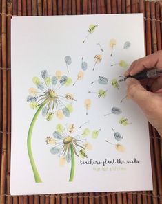 a person is writing on a piece of paper that has dandelions painted on it