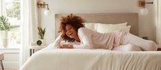 a woman laying on top of a bed in a bedroom