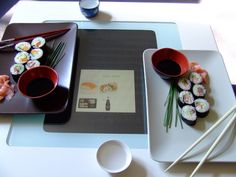 sushi and chopsticks are sitting on the table next to eachother