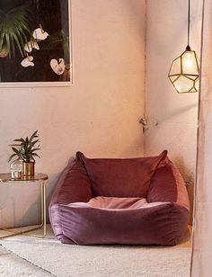 a bean bag chair sitting on top of a white rug next to a lamp and potted plant