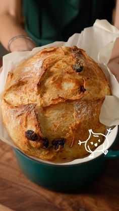 a baked bread in a green pot on a wooden table