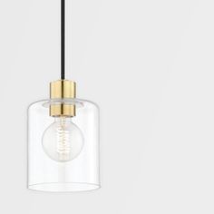 a clear glass and brass pendant light hanging from a black cord on a white wall