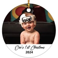 a baby's first christmas ornament with a smiling baby wearing a helmet