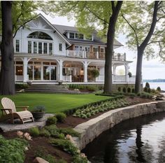 a large white house sitting on top of a lush green field next to a lake