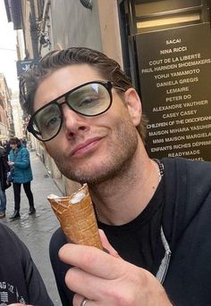 two men standing next to each other eating ice cream