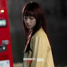 a woman standing next to a red phone booth