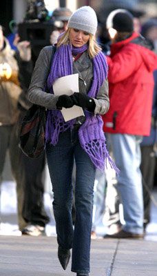 a woman walking down the street while wearing a purple scarf