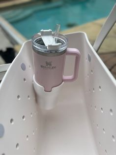 a pink and white cup sitting on top of a plastic container next to a swimming pool