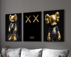 two gold and black mickey mouses are hanging on the wall above a couch in a living room