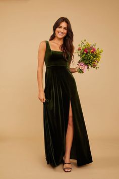 a woman in a long green dress holding a flower bouquet and smiling at the camera