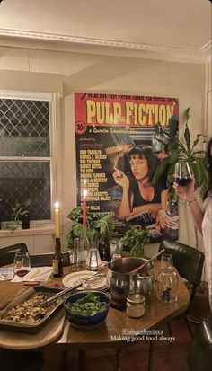 a woman standing in front of a table holding a glass of wine